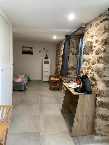 a room with a stone wall with a desk and a bedroom at Le Coquelicot in Najac