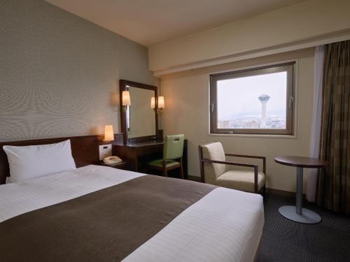 a hotel room with a bed and a desk and a window at Hotel Hokke Club Hakodate in Hakodate