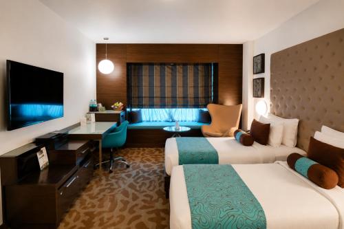 a hotel room with two beds and a desk at Pride Premier Bengaluru in Bangalore