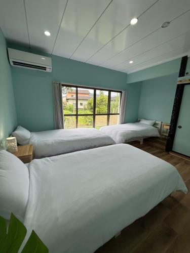 a room with three beds and a window at Yumigahama Eaglehouse 2 in Minamiizu