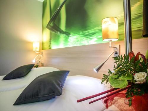 a bedroom with a bed with a flower arrangement on it at Hôtel Inn Design & Restaurant Rochefort in Rochefort