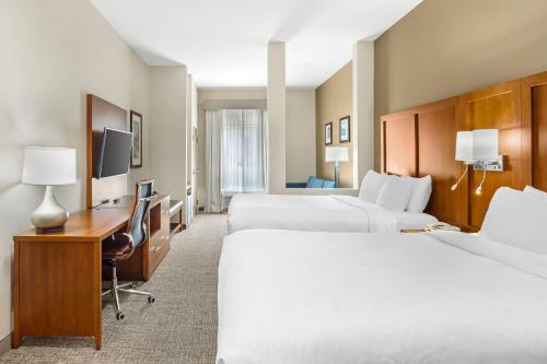 a hotel room with two beds and a desk at Comfort Suites Greensboro-High Point in Greensboro