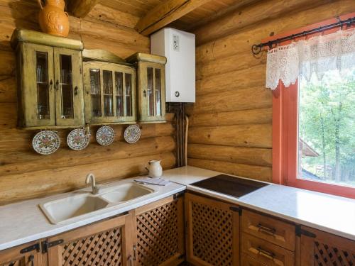 a kitchen with a sink and a window in a log cabin at Traditional wooden cottage in Cîmpu Cetăţii