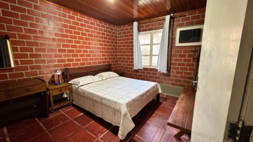 a bedroom with a bed and a brick wall at Casa da Paz - Gravatá in Gravatá
