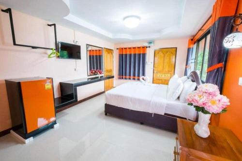 a bedroom with a bed and a television and flowers at Jirawan Hotel in Ko Samed