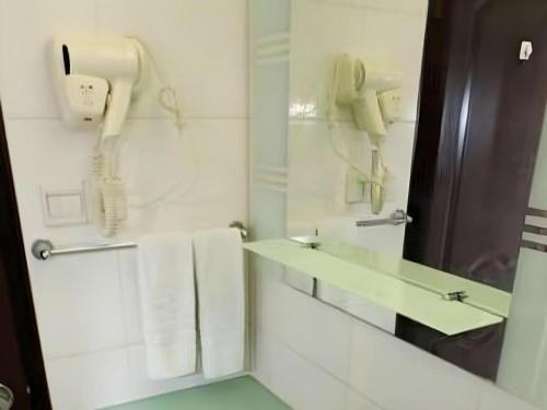 a white bathroom with a phone and towels at Hedong Hotel in Shenzhen