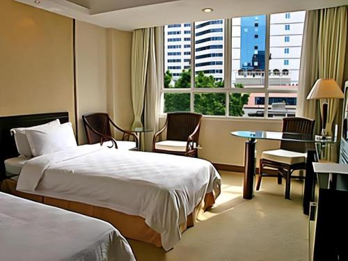 a hotel room with two beds and a table and a window at Hedong Hotel in Shenzhen
