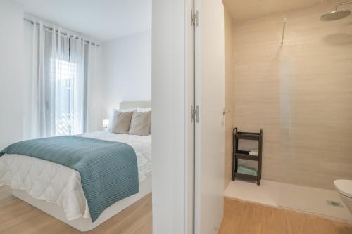 a white bedroom with a bed and a bathroom at Adhara lll in Torre del Mar