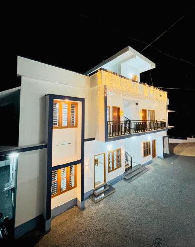 a large white building with a balcony at night at Zak Holidays Wayanad in Wayanad