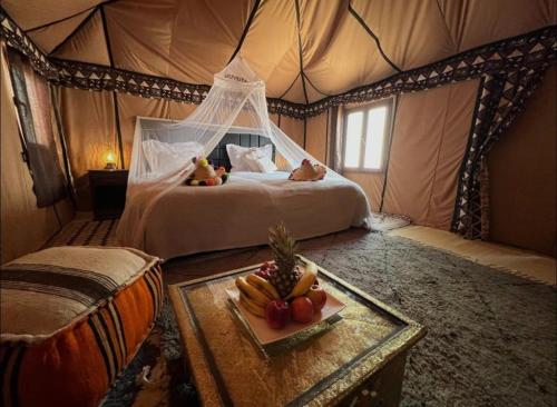 a bedroom with a bed in a tent with a tray of fruit at Bhbs accommodatie Maroc2 in Tazzarine