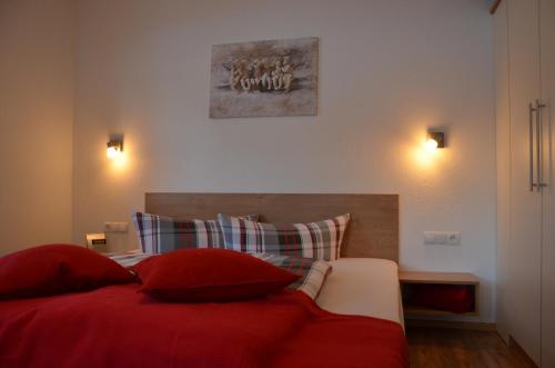 ein Schlafzimmer mit einem roten Bett mit zwei roten Kissen in der Unterkunft Appartement Alpenglühn in Oetz