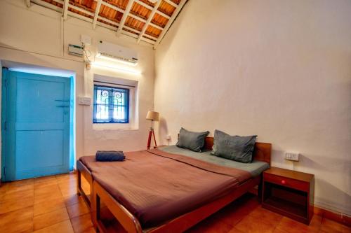 a large bed in a room with a blue door at Baga Wave Edge Cottages in Baga