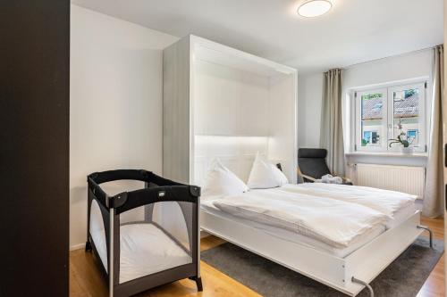a bedroom with a white bed and a black chair at Charmantes Haus mit eigenem Garten in Prien am Chiemsee