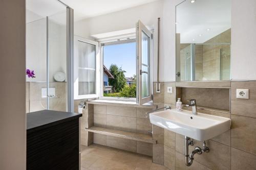 a bathroom with a sink and a shower and a window at Charmantes Haus mit eigenem Garten in Prien am Chiemsee