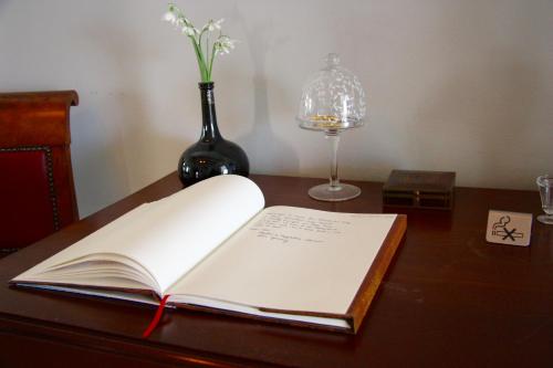 een open boek op een bureau met een vaas met bloemen bij 't Koetshuys in Heenvliet