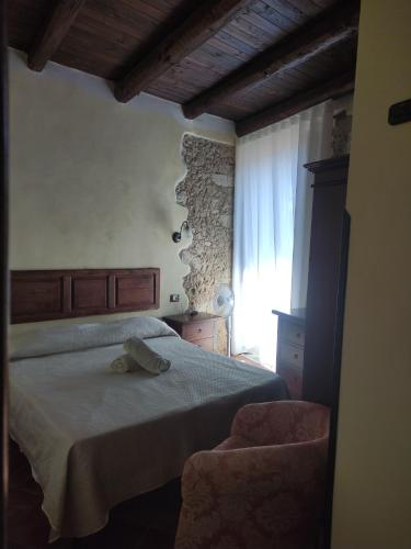 a bedroom with a bed and a chair and a window at Affittacamere Isidoro in Zaccanopoli