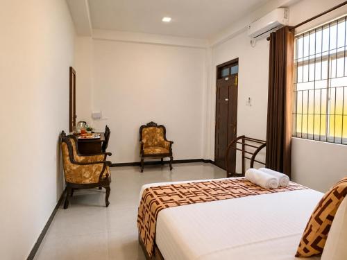a bedroom with a bed and two chairs and a desk at Air Route Transit in Seeduwa