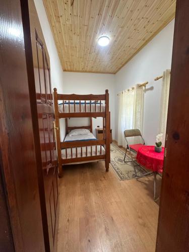 a room with two bunk beds and a red table at Bujtina Tata in Curraj