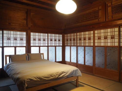 a bedroom with a bed in a room with windows at うみうたう in Yuwan