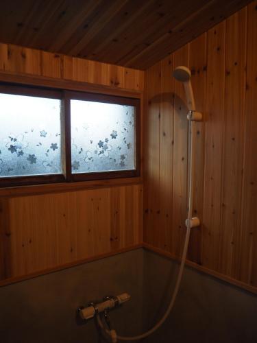 a shower in a bathroom with two windows and a tub at うみうたう in Yuwan