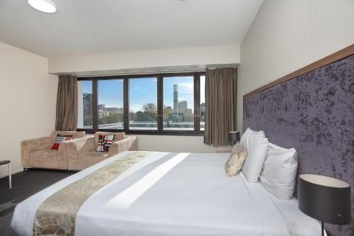 a bedroom with a large bed and a large window at Ramada Encore by Wyndham Palmerston North in Palmerston North