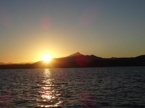 a sunset over the water with mountains in the background at Hotel Uhainak in Hendaye