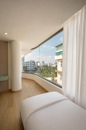 a bedroom with a white bed and a large window at Y Hotel Lý Hồng Thanh in Can Tho