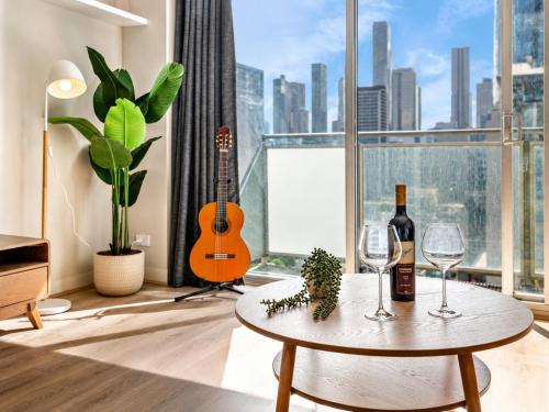 a room with a table with wine glasses and a guitar at Elevated CBD Retreat - Views & Pool & Sauna! in Melbourne