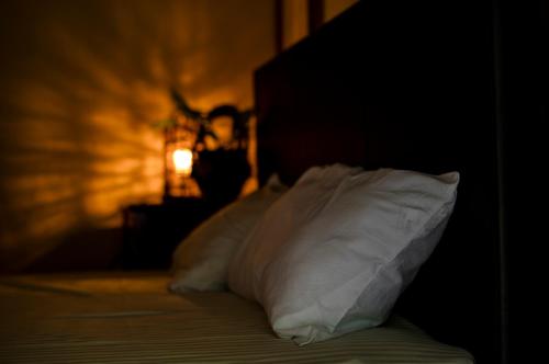 a bed with white pillows in a dark room at Kume Guest House in Kumejima