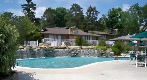 a swimming pool with a waterfall in front of a house at Tan-Tar-A Estates in Damsel