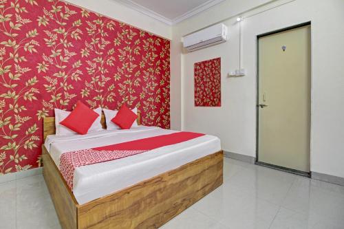 a bedroom with a bed with a red wall at Hotel O Sai Executive Lodging in Māngvādi
