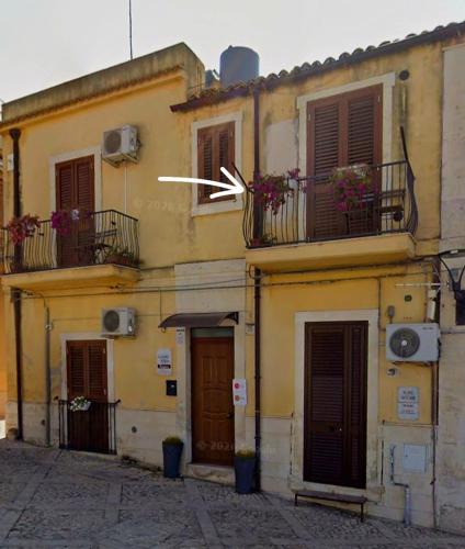 a yellow building with balconies and doors and windows at La Perla Di Noto in Noto