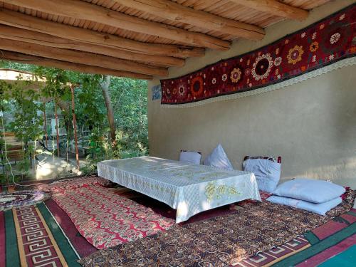 a bed sitting on a rug in a room at Rahima's Guest House in Tadzhimi