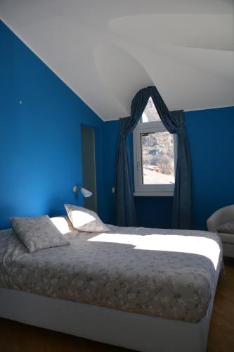 a bedroom with blue walls and a bed with a window at Villa del Gusto in Bellinzona