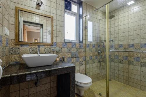 a bathroom with a sink and a toilet and a mirror at The Baga Pescador in Baga