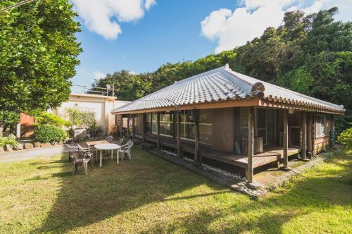 a house with a table and chairs in the yard at Kume Guest House in Kumejima