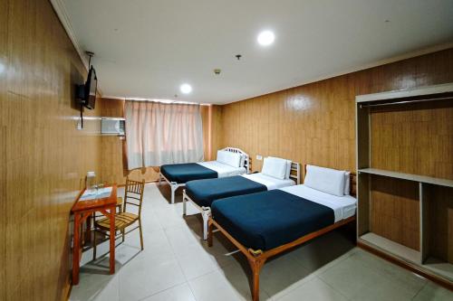 a room with four beds and a table and chairs at Hotel Uno in Davao City