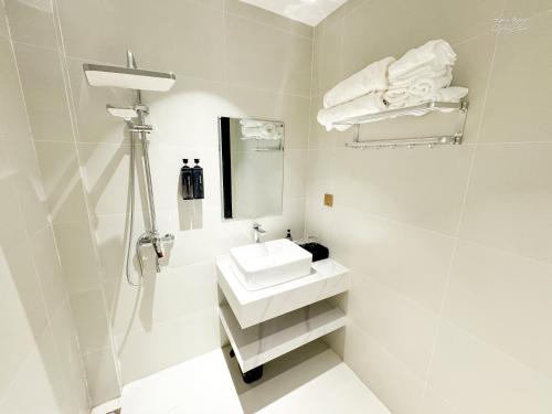 a white bathroom with a sink and a mirror at Verdant Apartment & Hotel in Dong Hoi