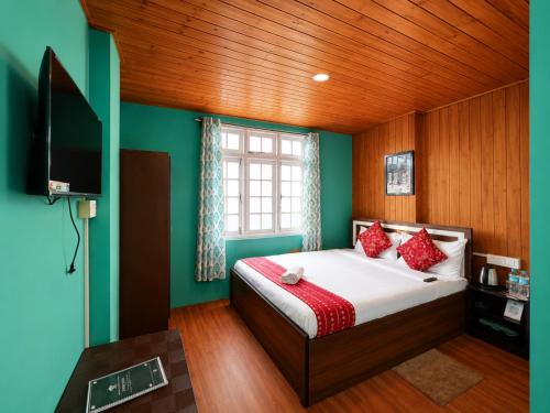 a bedroom with a bed and a flat screen tv at Hotel Pinecrest Inn Darjeeling With Mountain View Room And Parking - Restaurant Facility in Darjeeling