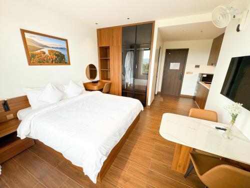a bedroom with a white bed and a desk at Verdant Apartment & Hotel in Dong Hoi