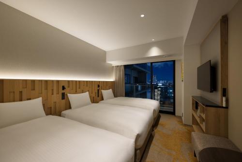 a hotel room with two beds and a television at Miyako City Osaka Hommachi in Osaka
