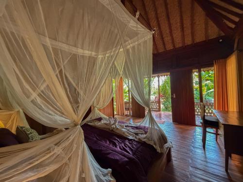a bedroom with a bed with mosquito nets at Pondok Risky in Tegalalang