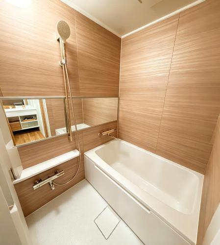 a bathroom with a white tub and wooden walls at ETSU 悦 HOTEL Chuo Ward Tokyo 1-2BDR House in Tokyo