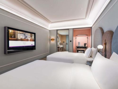 a hotel room with two beds and a flat screen tv at Mercure Lanzhou West in Lanzhou