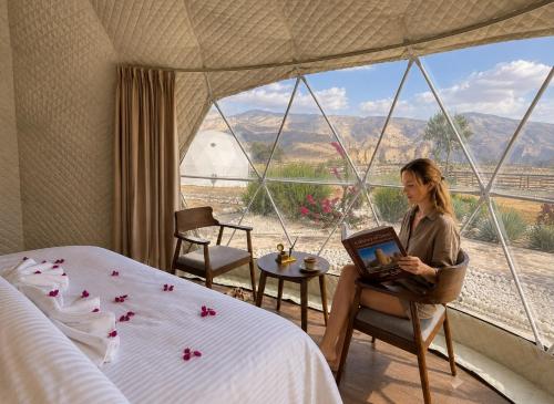 a woman sitting in a chair in a room with a window at Jabal shams domes in Sa‘ab Banī Khamīs