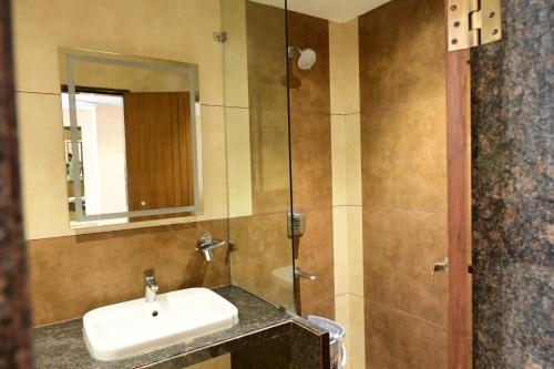 a bathroom with a sink and a shower at IJ Crowne in Mysore