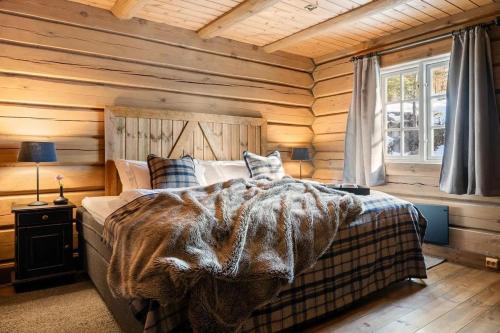 a bedroom with wooden walls and a bed with a blanket at Solskiva 23 in Trysil