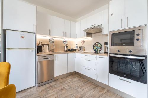 a kitchen with white cabinets and stainless steel appliances at Paz Ocean View, 2 Air Conditioners, Wifi, Heated pool in San Miguel de Abona