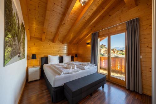 a bedroom with a large bed and a large window at Chalet La Tirelire in Nendaz