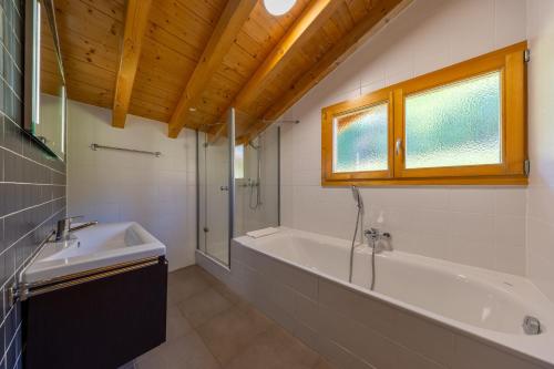 a bathroom with a tub and a shower and a sink at Chalet La Tirelire in Nendaz